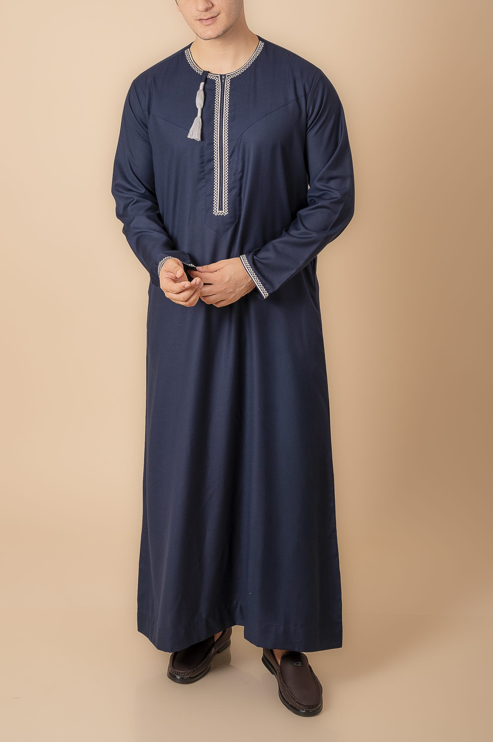Navy Blue Omani Thobe with Light grey / silver grey Embroidery & Tassel – Front View Navy blue Omani thobe with Light grey / silver grey geometric embroidery and tassel for men
