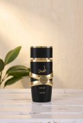 Lattafa Asad 100ml perfume for men in a luxury black and gold bottle with a circular lion crest shield next to its original packaging box.